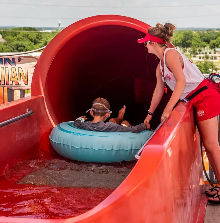 lifeguard helping child down a slide